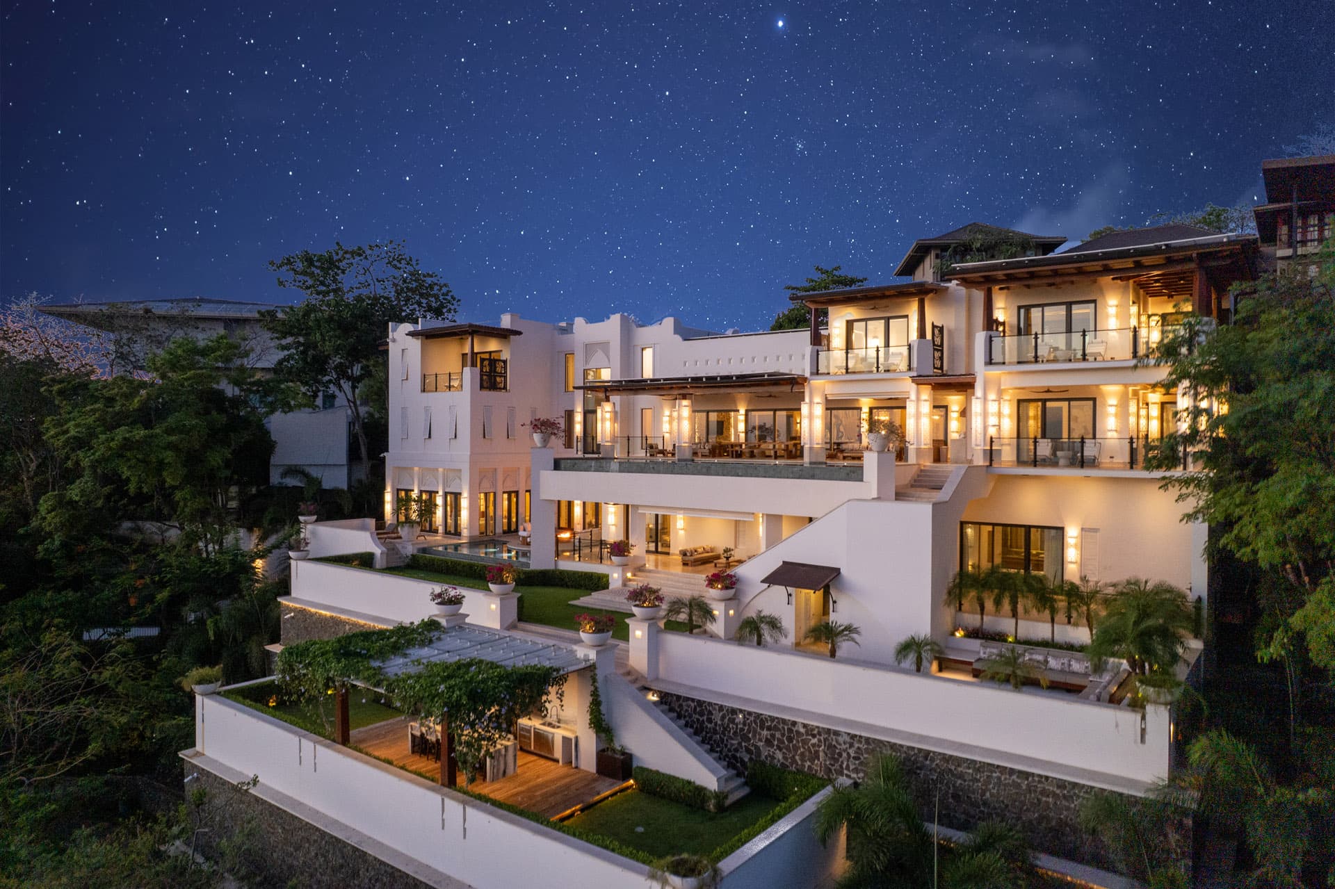 Villa Luciérnaga illuminated at night, all terrace levels glowing under stars